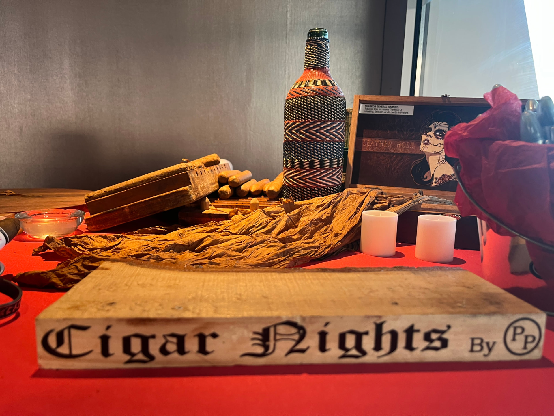 Cigar Nights branded rolling station with tobacco leaf, cigars and candlelight