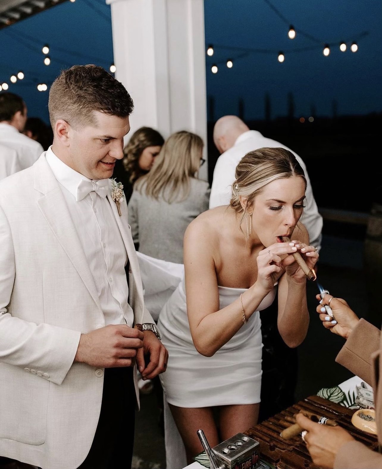 Bride lighting a hand-rolled cigar at her wedding cigar bar